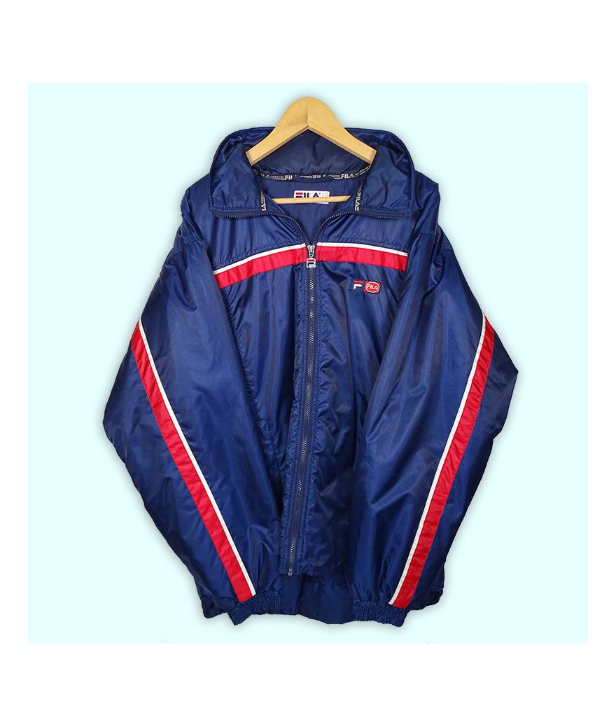 Manteau Fila bleu marine, deux poches à zip. Logo en patch brodé au niveau du coeur. Capuche se roule dans le col